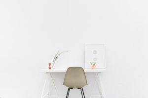 Ein Schreibtisch mit einem Stuhl vor einer weißen Wand